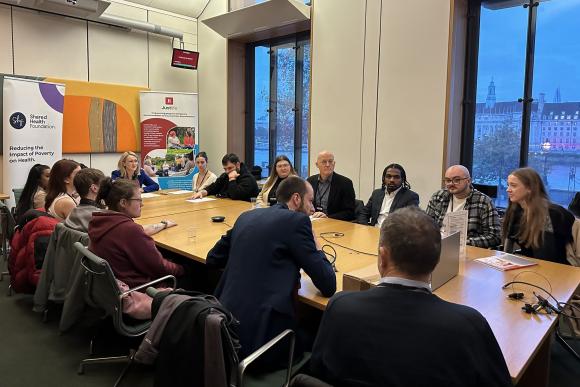A group of young people speaking in Parliament, with charities and government departments around a table.